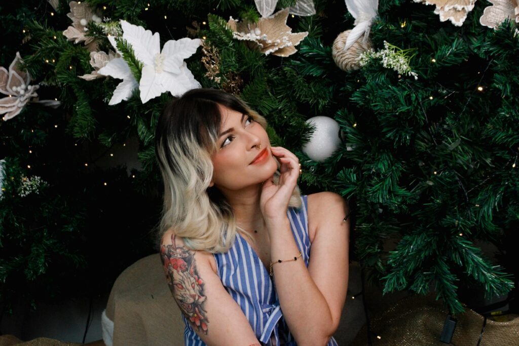 Smiling woman with floral tattoo enjoying Christmas holiday decorations in São Paulo.